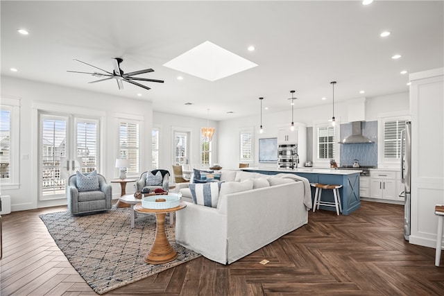 living room featuring ceiling fan, a skylight, and dark parquet floors