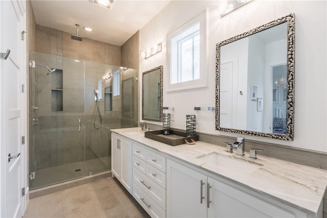 bathroom featuring double vanity, a shower stall, and a sink