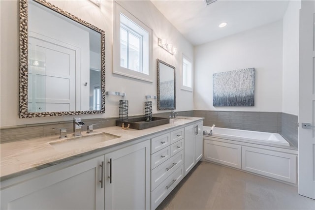 bathroom with a sink, double vanity, and a garden tub