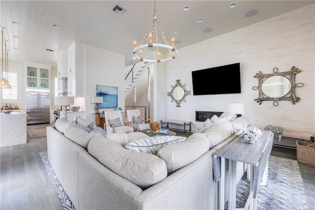 living area with wood finished floors, a notable chandelier, visible vents, wooden ceiling, and stairs