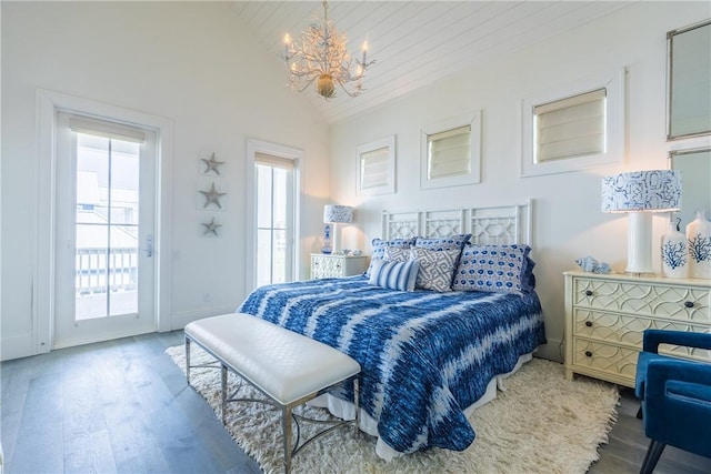 bedroom featuring vaulted ceiling, a notable chandelier, access to outside, and wood finished floors