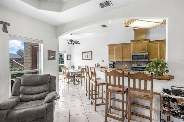 15426 Cuttysark St, Corpus Christi, TX 78418 - kitchen with appliances with stainless steel finishes, ceiling fan, brown cabinets, decorative backsplash, and light tile patterned floors