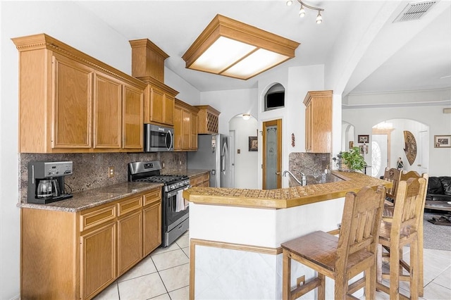 15426 Cuttysark St, Corpus Christi, TX 78418 - kitchen featuring stainless steel appliances, arched walkways, light tile patterned floors, a peninsula, and tasteful backsplash