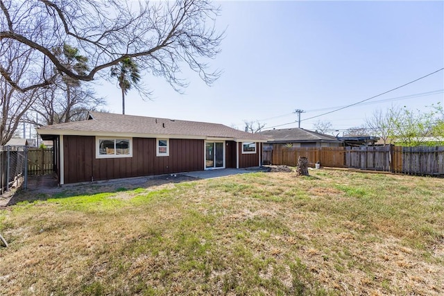 back of house with a fenced backyard and a lawn