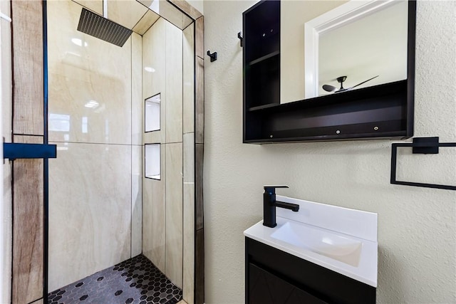 bathroom featuring vanity, a shower stall, and a textured wall