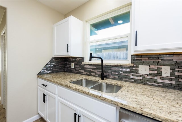 kitchen featuring backsplash, dishwasher, white cabinetry, and a sink