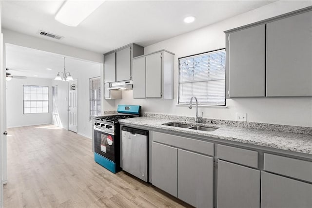 kitchen with appliances with stainless steel finishes, decorative light fixtures, sink, gray cabinetry, and light hardwood / wood-style flooring