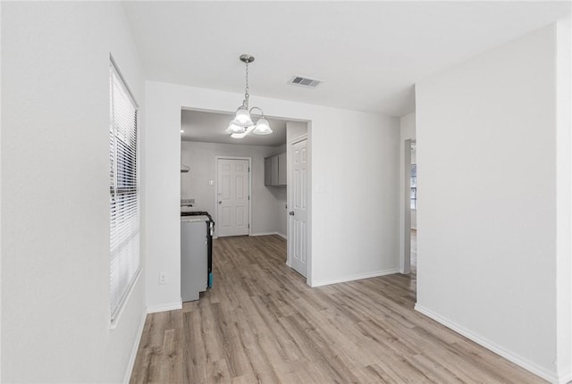 kitchen featuring range, decorative light fixtures, an inviting chandelier, and light hardwood / wood-style flooring