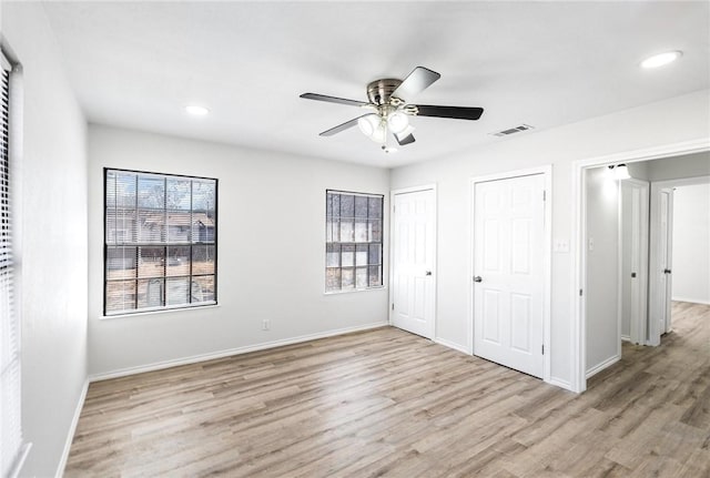 unfurnished bedroom with multiple windows, multiple closets, ceiling fan, and light hardwood / wood-style flooring