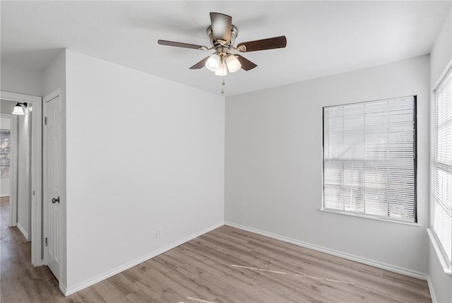 empty room with ceiling fan, plenty of natural light, and light hardwood / wood-style floors