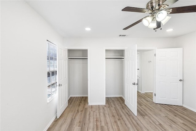 unfurnished bedroom featuring two closets, ceiling fan, and light wood-type flooring