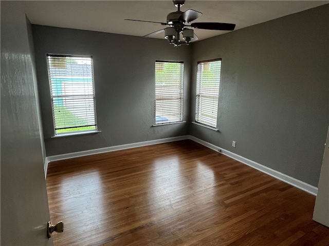 empty room featuring dark hardwood / wood-style flooring, a wealth of natural light, and ceiling fan