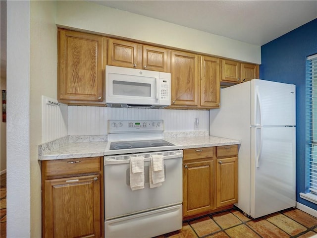 kitchen with brown cabinets, white appliances, light countertops, and light tile patterned floors