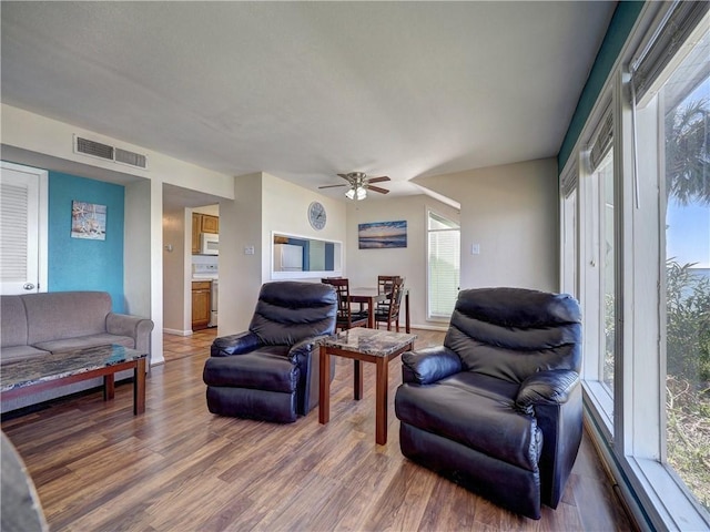 living room with baseboards, wood finished floors, visible vents, and a ceiling fan