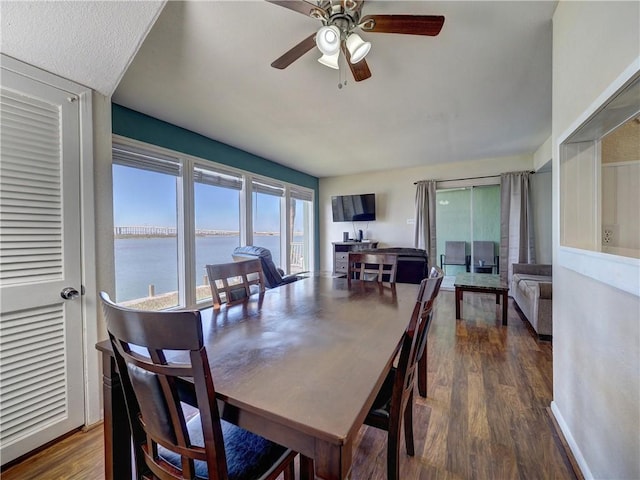 dining area with dark wood finished floors, a ceiling fan, and baseboards