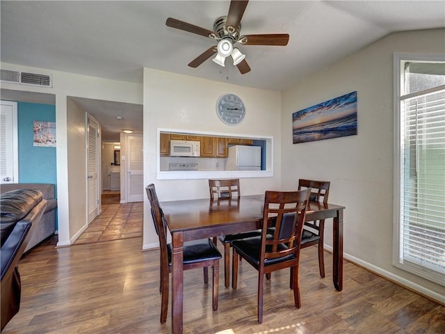 dining space featuring lofted ceiling, wood finished floors, a ceiling fan, visible vents, and baseboards