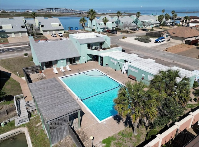 pool featuring a patio, a water view, fence, and a residential view