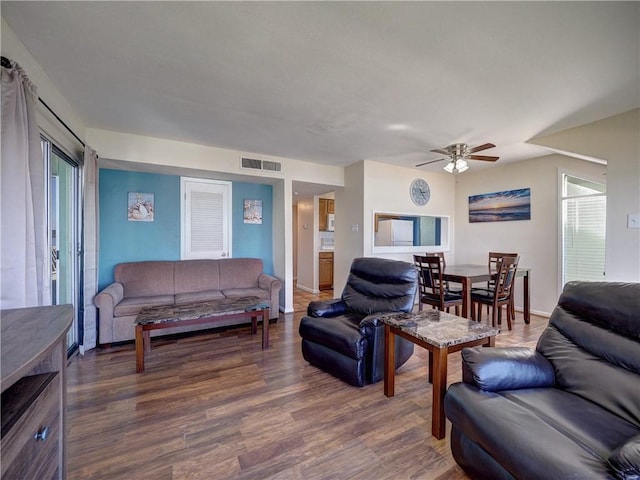 living area with visible vents, ceiling fan, baseboards, and wood finished floors