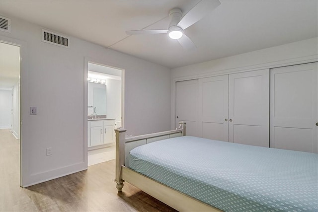 bedroom with ceiling fan, sink, connected bathroom, light hardwood / wood-style floors, and a closet