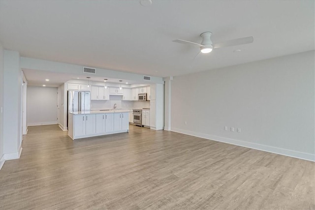 unfurnished living room with light hardwood / wood-style floors, ceiling fan, and sink