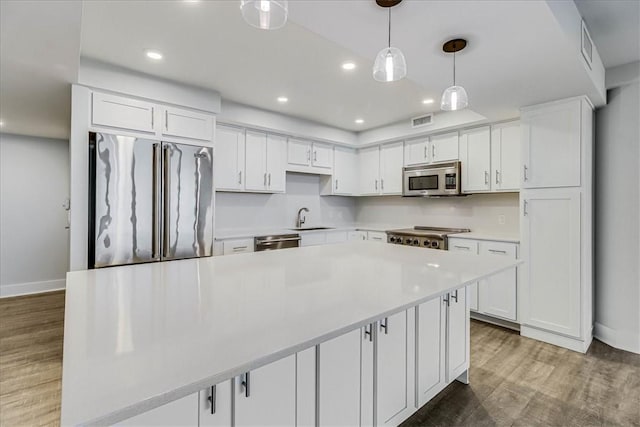 kitchen with pendant lighting, sink, dark hardwood / wood-style floors, white cabinetry, and stainless steel appliances