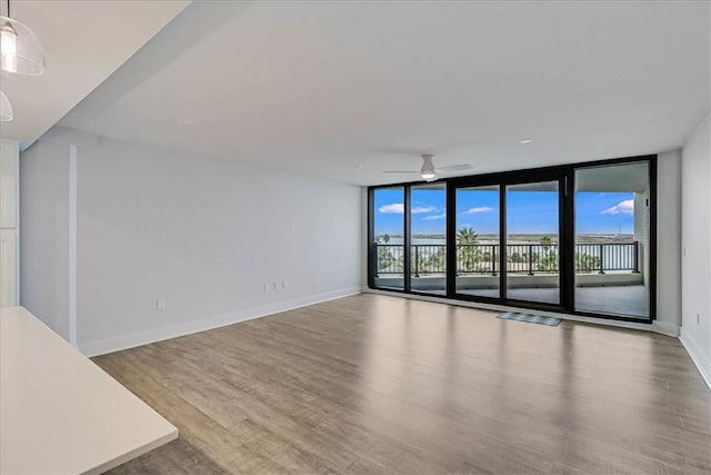 interior space featuring light hardwood / wood-style flooring, a wall of windows, and ceiling fan