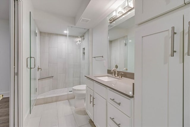 bathroom featuring tile patterned flooring, vanity, a shower with shower door, and toilet