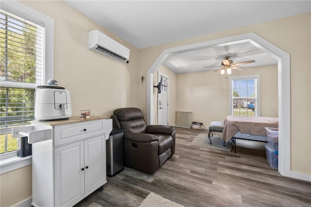 living area with an AC wall unit, arched walkways, a ceiling fan, dark wood-style floors, and radiator heating unit