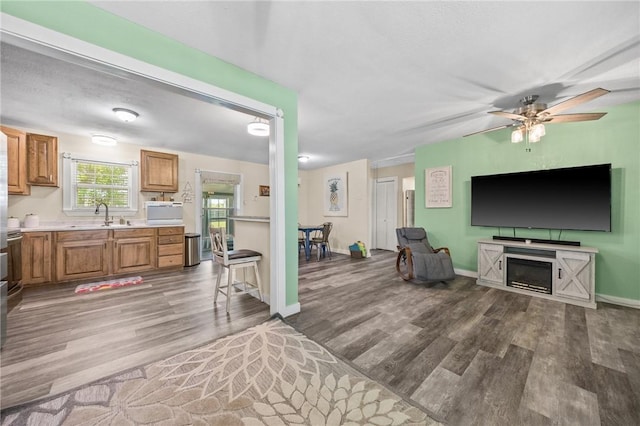 living room with light wood-style flooring, a ceiling fan, and baseboards
