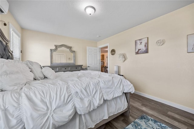 bedroom with baseboards, dark wood-type flooring, and a wall mounted air conditioner