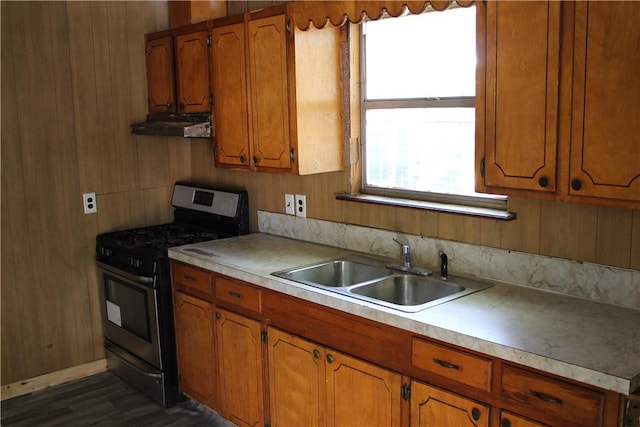 kitchen featuring wood walls, sink, and gas range