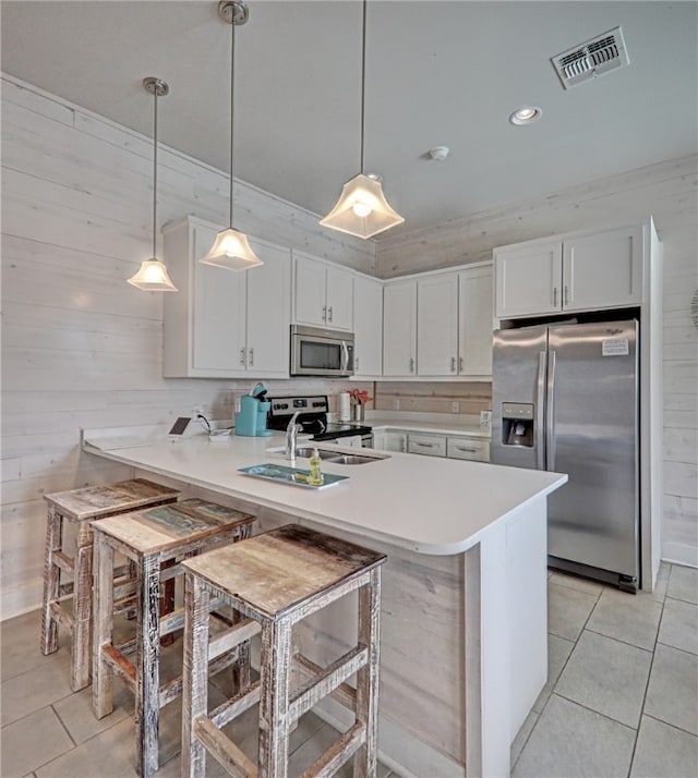 kitchen with stainless steel appliances, white cabinets, pendant lighting, and kitchen peninsula