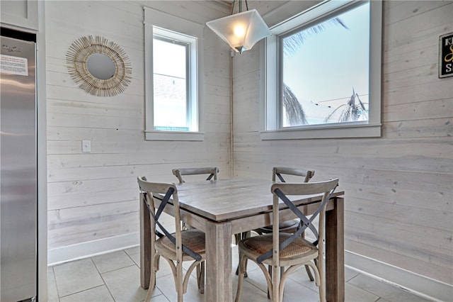 tiled dining space featuring wood walls