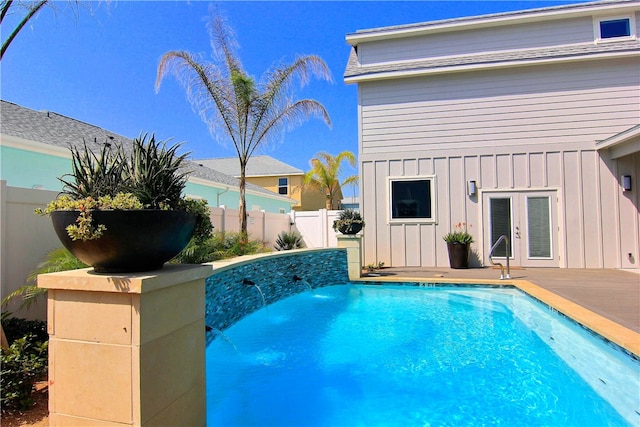 view of swimming pool with french doors and pool water feature