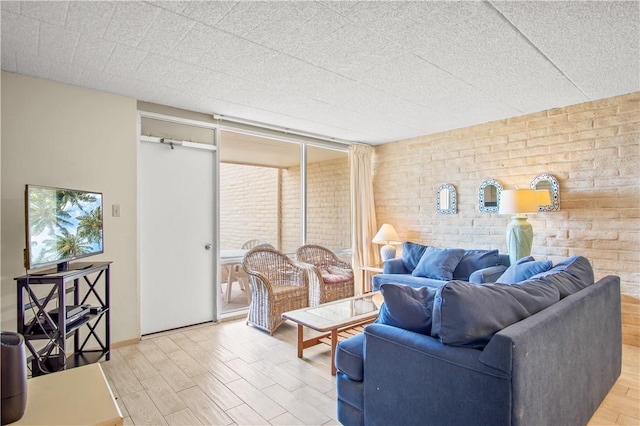 living room with hardwood / wood-style flooring, floor to ceiling windows, and brick wall