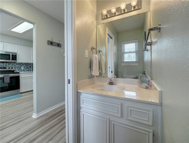 bathroom with wood-type flooring, vanity, toilet, and tasteful backsplash