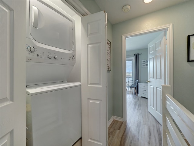 washroom with light hardwood / wood-style floors and stacked washer / dryer