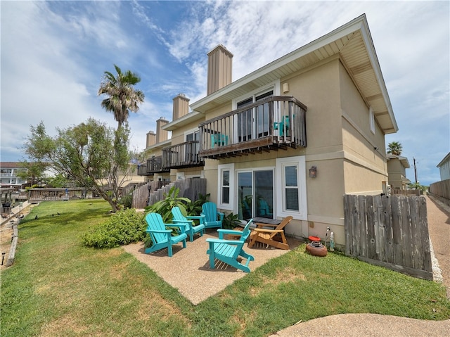 rear view of property featuring a yard and a balcony