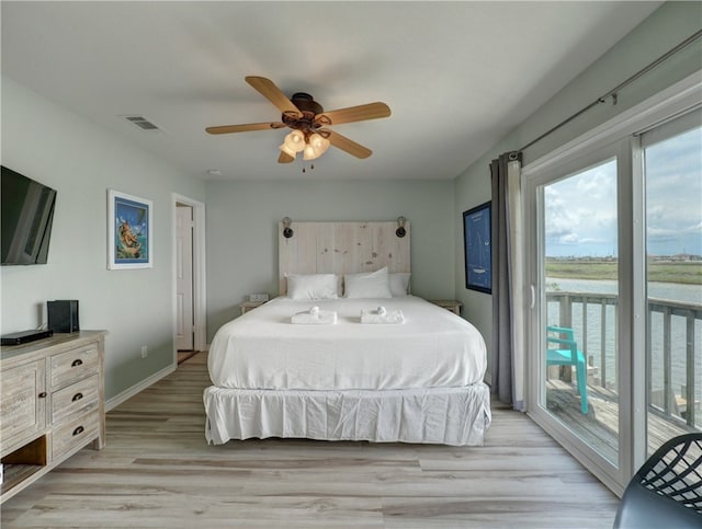 bedroom featuring ceiling fan, a water view, light hardwood / wood-style floors, and access to exterior