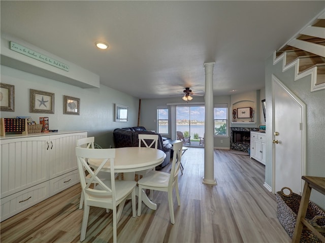 dining space with decorative columns, ceiling fan, and light wood-type flooring