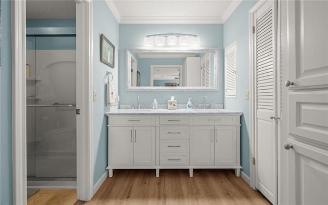 bathroom featuring vanity, crown molding, a shower with door, and a textured ceiling