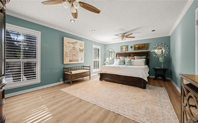 bedroom with ceiling fan, ornamental molding, a textured ceiling, and light wood-type flooring