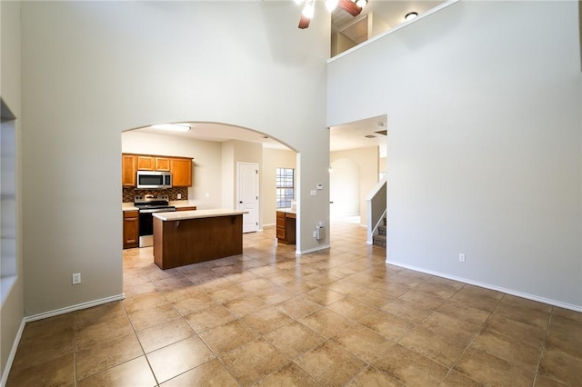 kitchen with a kitchen island, tasteful backsplash, a breakfast bar area, ceiling fan, and stainless steel appliances