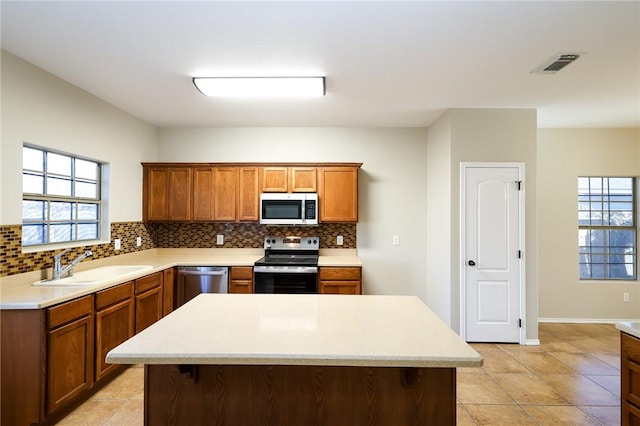 kitchen featuring sink, backsplash, stainless steel appliances, and a center island