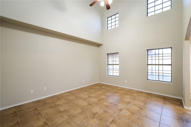 interior space with a high ceiling, tile patterned flooring, a wealth of natural light, and ceiling fan