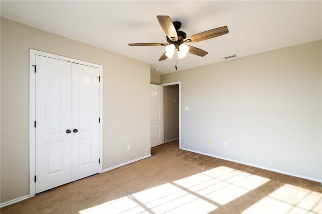 unfurnished bedroom featuring carpet floors, a closet, and ceiling fan