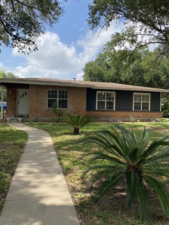 ranch-style home featuring brick siding and a front lawn
