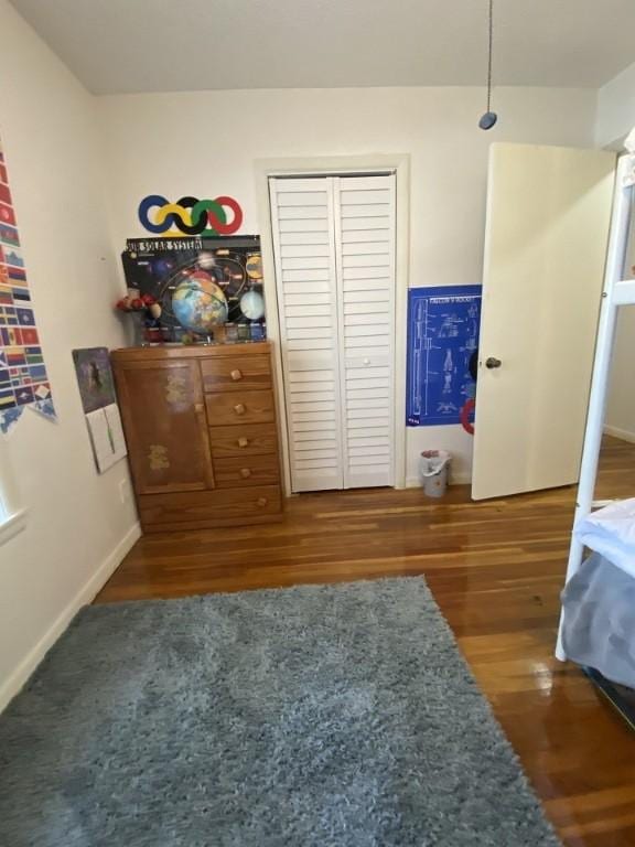 bedroom featuring wood finished floors, baseboards, and a closet