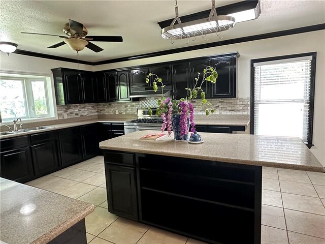 110 Amistad St, Corpus Christi, TX 78404 - kitchen with dark cabinets, stainless steel range with gas cooktop, a sink, light tile patterned floors, and ornamental molding