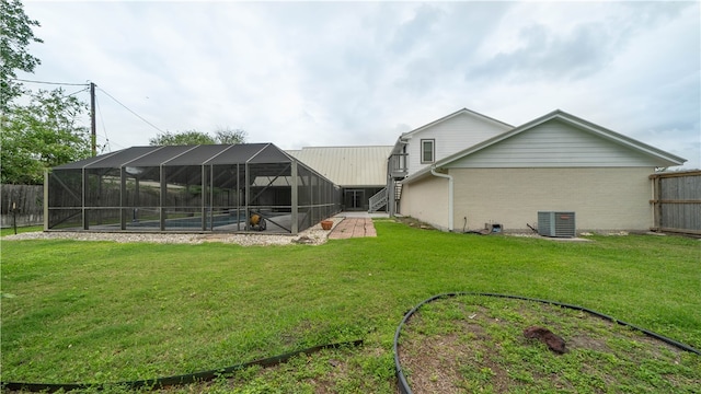 back of house with cooling unit, a patio area, a swimming pool, a yard, and a lanai